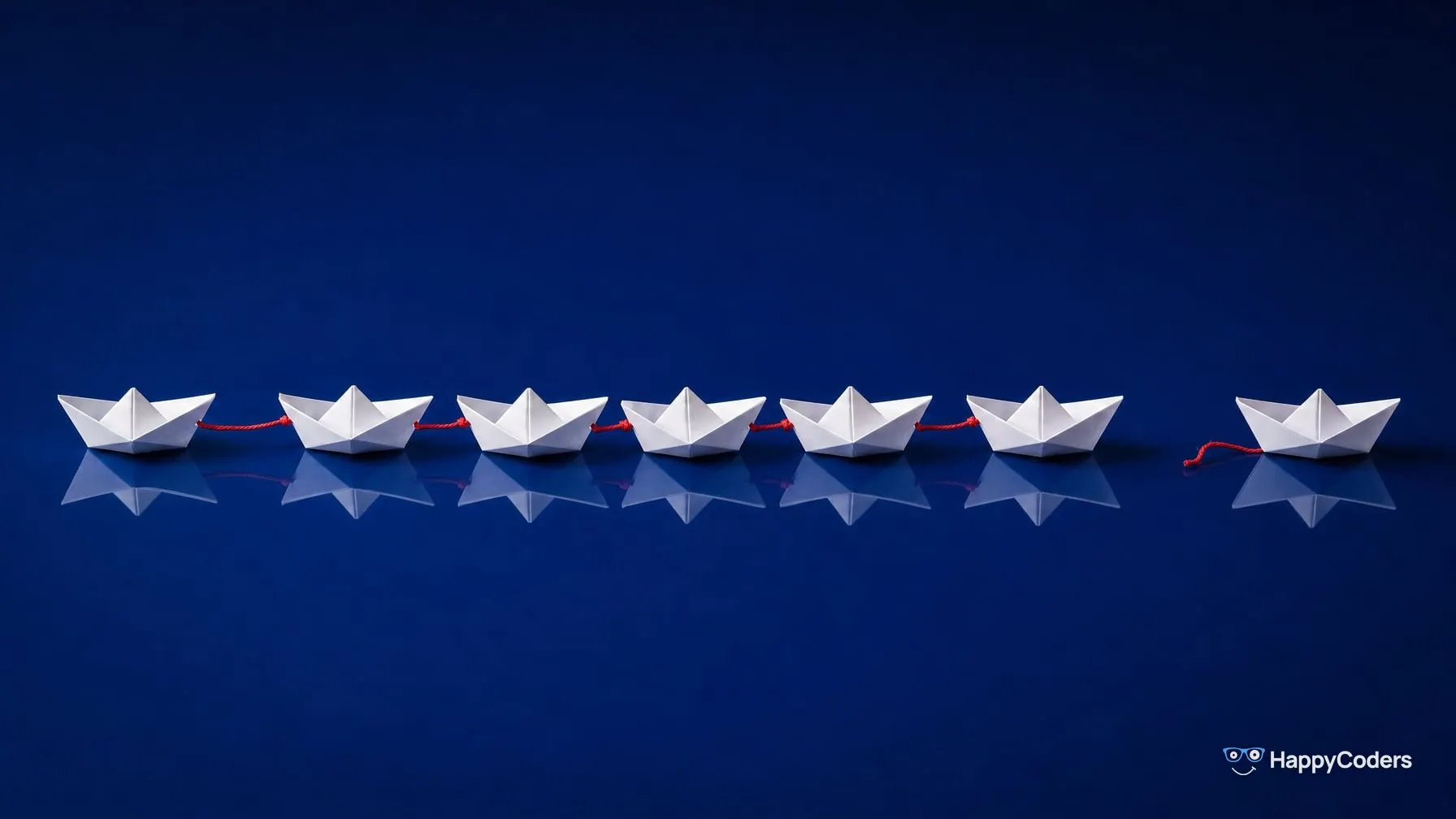 White paper boats tied into a line with red string; the front boat on the right is untied